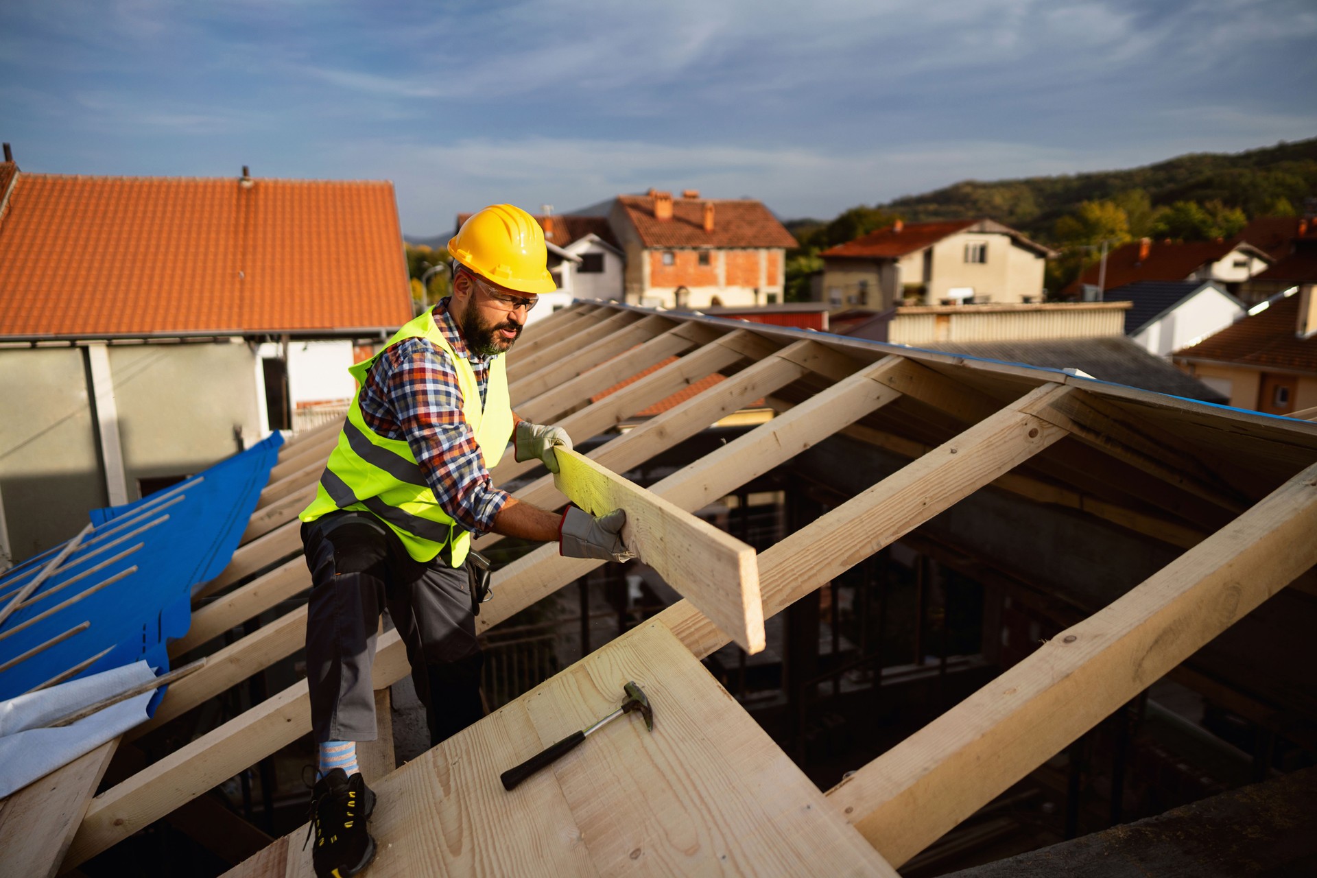 Caucasian male roofer, working on a roof beam on a construction site